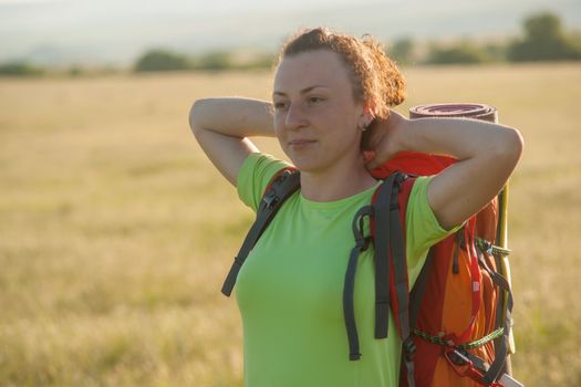 Happy smiling woman in field. Green grass in foreground and clear sky in background.