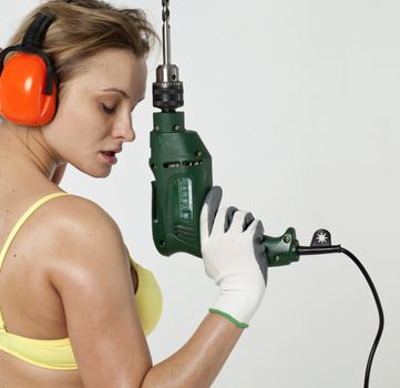 Young sexy woman holding a construction drill