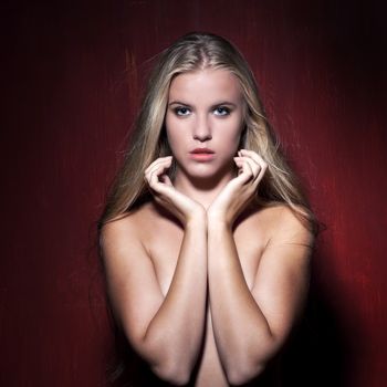 Sexy nude model in dark red studio