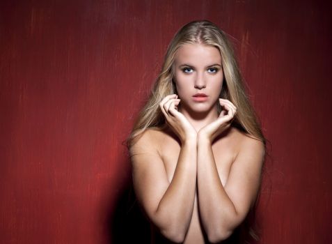 Sexy nude model in dark red studio