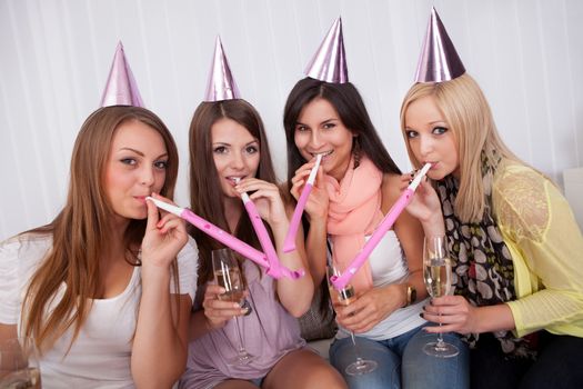 Four attractive females celebrating with a champagne and cone caps