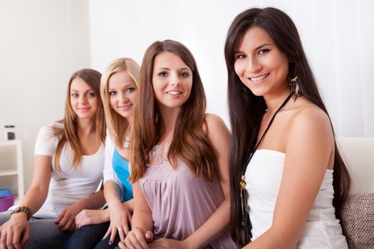 Row of beautiful stylish young ladies sitting on a couch in a living room