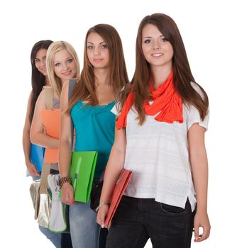 Four beautiful young female students standing in a receding row with folders of notes under their arms isolated on white