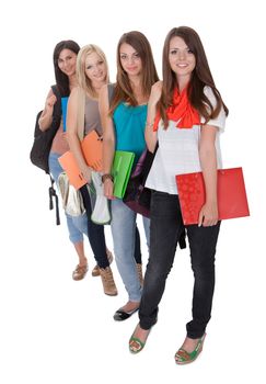 Four beautiful young female students standing in a receding row with folders of notes under their arms isolated on white