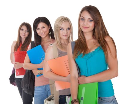 Four beautiful young female students standing in a receding row with folders of notes under their arms isolated on white