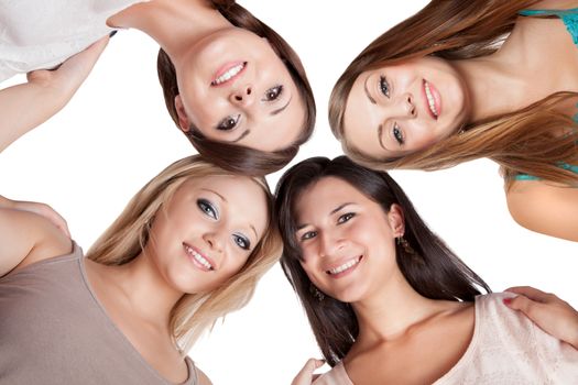 Four attractive young woman looking down at the camera with their heads close together isolated on white