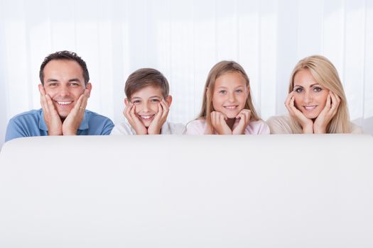 Portrait Of  Happy Family Behind White Sofa, Indoors