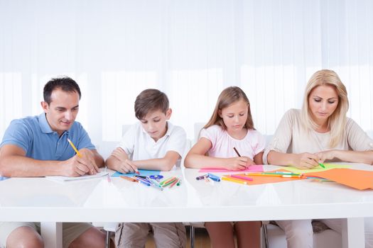 Young Family Drawing Together With Colorful Pencils And Crayons At Home