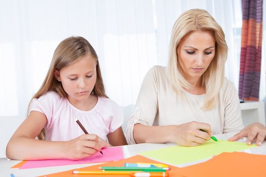 Mother And Daughter Drawing Together With Colorful Pencils And Crayons At Home