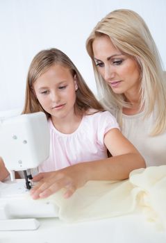 Portrait Of A Beautiful Young Girl Sewing With Her Mother At Home