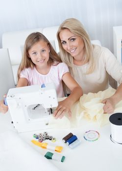 Portrait Of A Beautiful Young Girl Sewing With Her Mother At Home