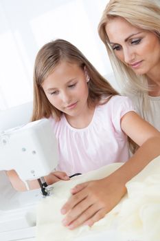 Portrait Of A Beautiful Young Girl Sewing With Her Mother At Home