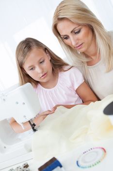 Portrait Of A Beautiful Young Girl Sewing With Her Mother At Home