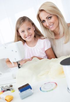 Portrait Of A Beautiful Young Girl Sewing With Her Mother At Home