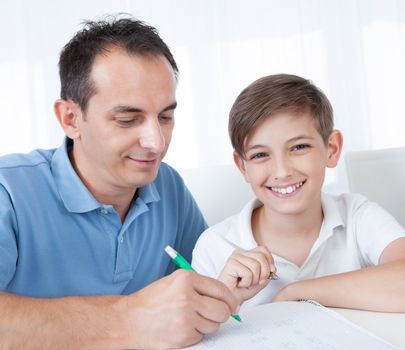 Portrait Of Father And Son Doing Homework At Home