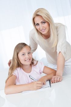 Teacher Helping Girl With Exercise At School