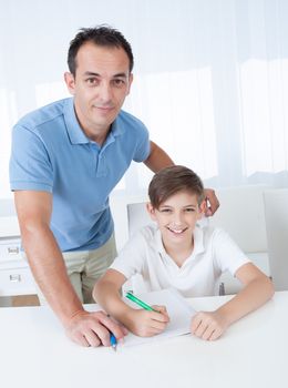 Portrait Of A Boy Doing Homework With His Father At Home