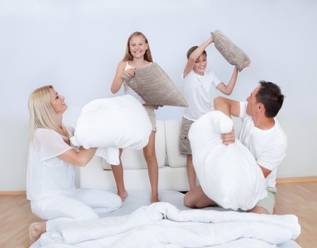 Playful Family Having A Pillow Fight Together On Bed In Bedroom