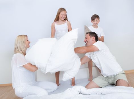 Playful Family Having A Pillow Fight Together On Bed In Bedroom