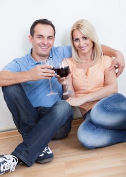 Couple Sitting Between Cardboard Boxes And  Holding Wine Glass, Indoors