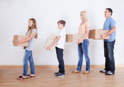 Parents And Two Children With Cardboard Boxes, Indoors