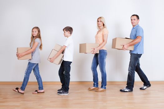 Parents And Two Children With Cardboard Boxes, Indoors