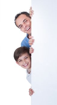Portrait Of Father and Boy Peeping Behind Blank Board On White Background