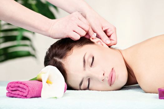 Pretty woman on ear massage in salon