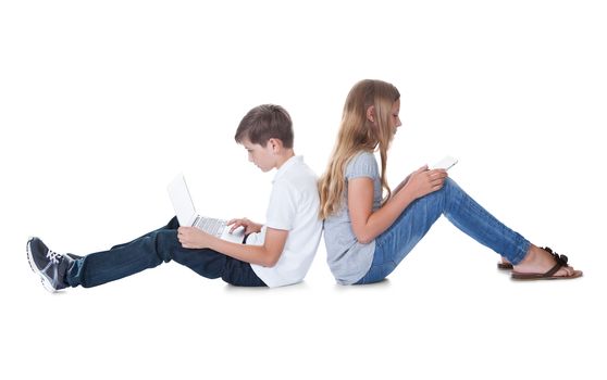 Boy And Girl Sitting Back To Back Using Laptop And Digital Tablet Isolated On White Background