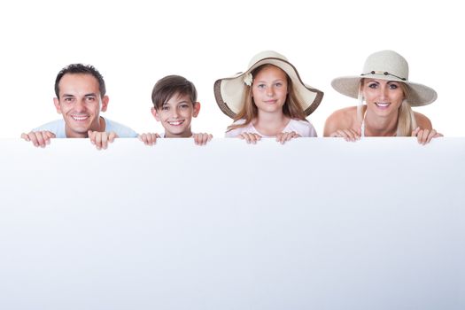 Portrait Of Family With Two Children Behind Blank Board On White Background