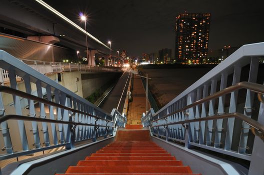 illuminated stairs going down near huge highway in night city