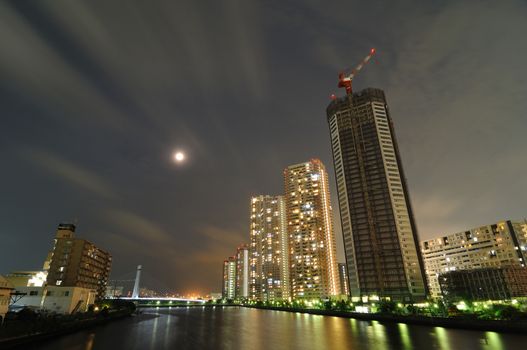 new skyscraper buildings rising up over river waters in modern city, Tokyo Japan