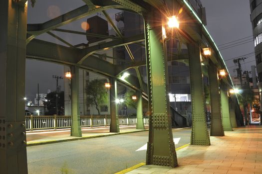 night street and pathway trough metallic arc bridge in Tokyo
