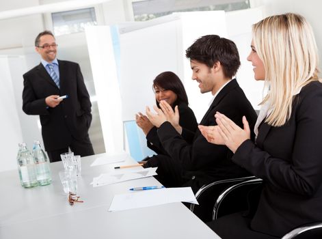 Group of business people at presentation applauding to the lecturer