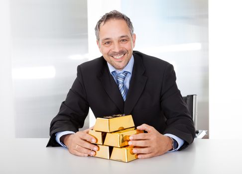 Portrait of happy businessman with golden bars at the office