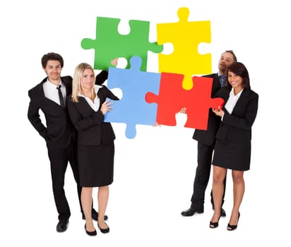 Group of business people assembling jigsaw puzzle. Isolated on white