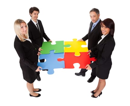 Group of business people assembling jigsaw puzzle. Isolated on white
