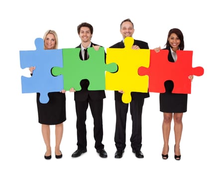 Group of business people assembling jigsaw puzzle. Isolated on white