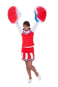 Smiling beautiful cheerleader with pompoms. Isolated on white