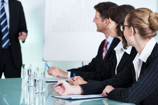 A senior business executive delivering a presentation to his colleagues during a meeting or in-house business training