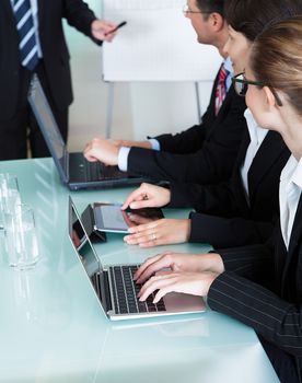 Cropped view image of a row of businesspeople working on laptops and tablets during a presentation or meeting