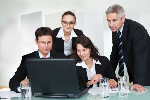 Confident successful business team of diverse executives posing in an office together smiling happily at the camera