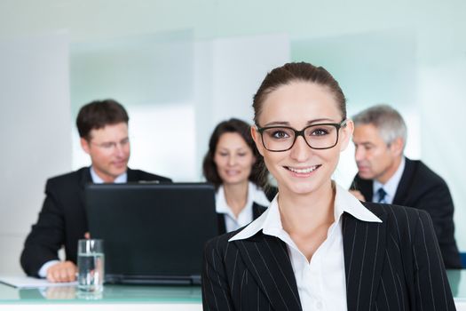 Corporate advancement and leadership concept with a confident smiling attractive businesswoman wearing glasses standing with her arms folded