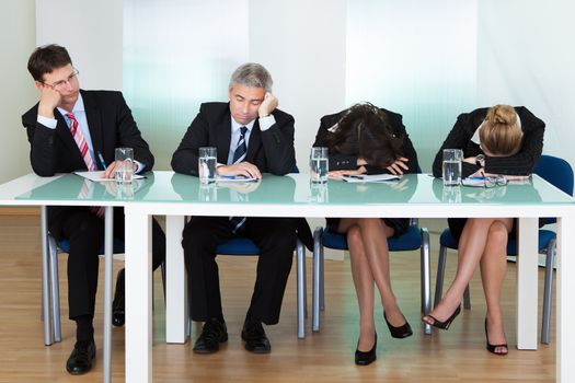 Bored panel of professional judges or corporate interviewers lounging around on a table napping as they wait for something to happen