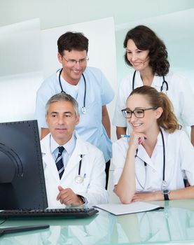 Doctors having a meeting seated at a table in front of a computer discussing case histories