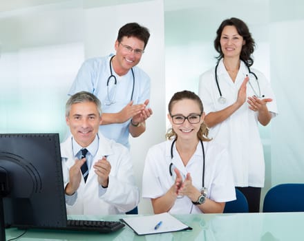 Happy medical team compridsing male and female doctors smiling broadly and giving a thumbs up of success and hope