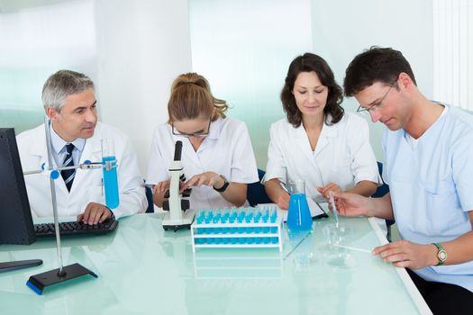 Paramedical or technical staff grouped together looking at a computer in a laboratory