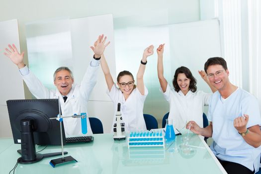 Laboratory technicians or medical technologists sitting around a lab bench conducting tests on a rack of test tubes