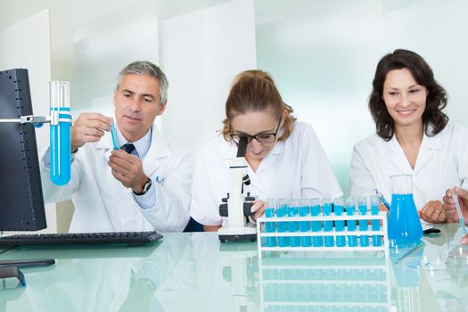 Paramedical or technical staff grouped together looking at a computer in a laboratory