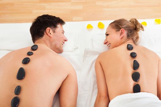 Couple enjoying a hot stone massage in a spa where heated stones are placed along the spine to relax the muscles